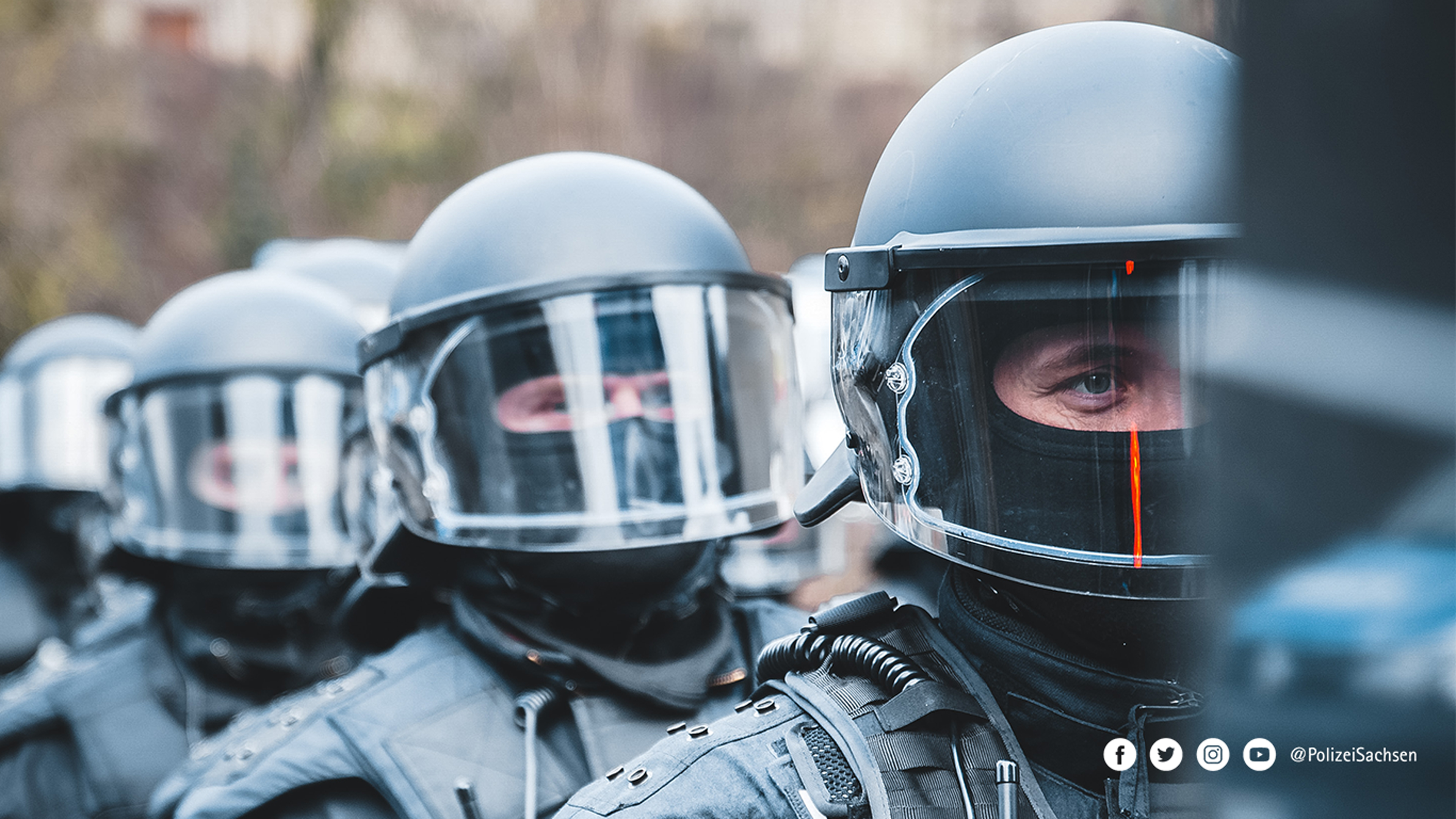 Nahaufnahme: Bereitschaftspolizisten mit Helm blicken in die Kamera.