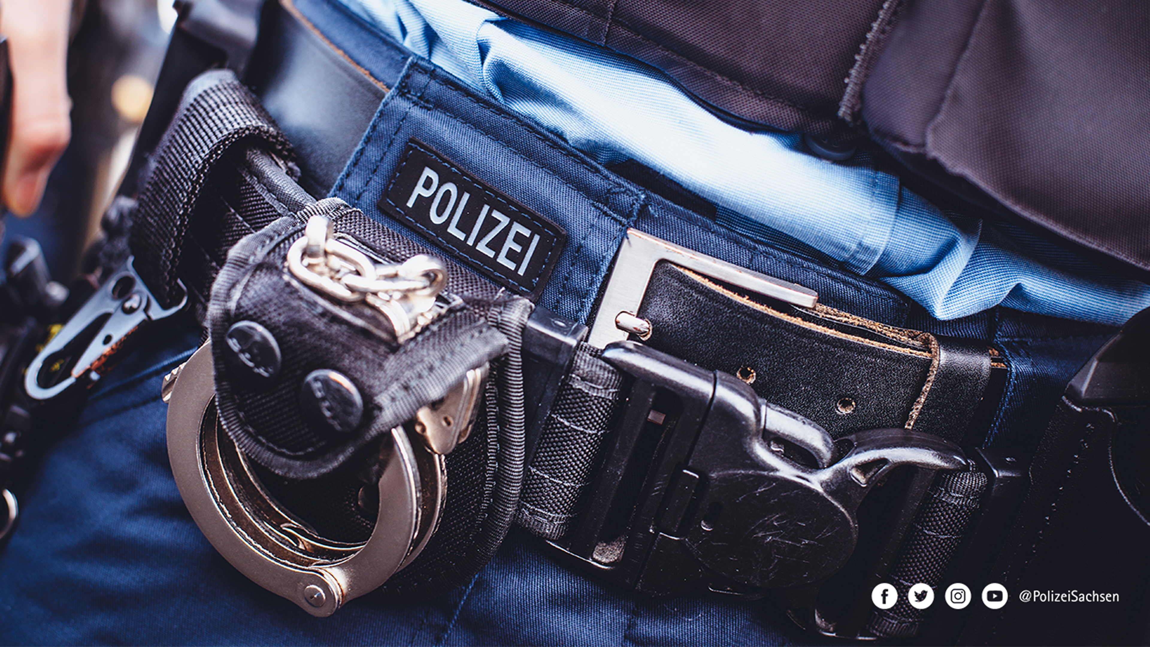 Ein Bund Handschellen hängt an einem Gürtel. Darüber der Schriftzug Polizei.