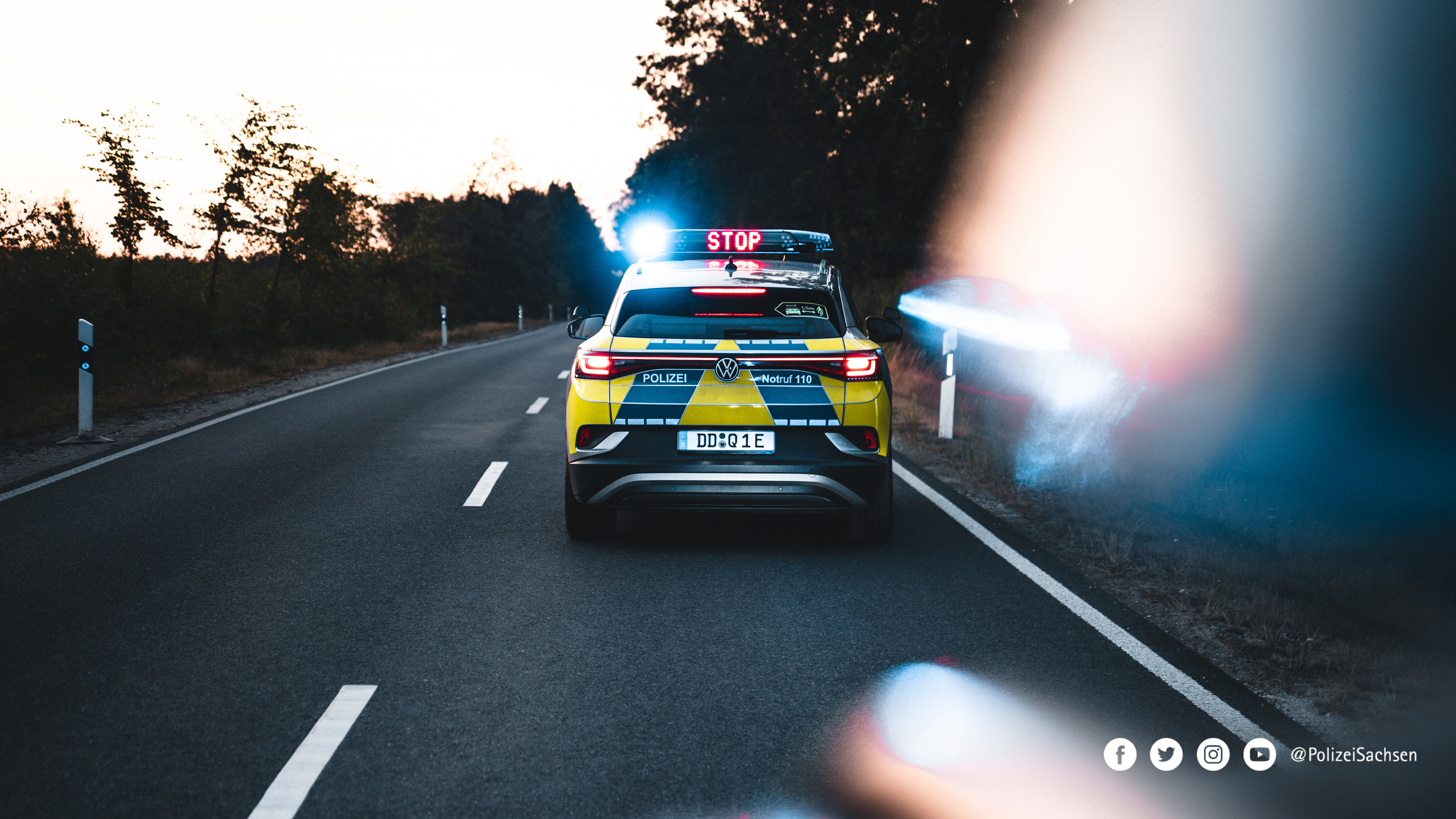 Ein Streifenwagen der Polizei Sachsen bei einer Verkehrskontrolle auf einer Landstraße. In der Sondersignalanlage ist der Begriff »Stop« eingeblendet.