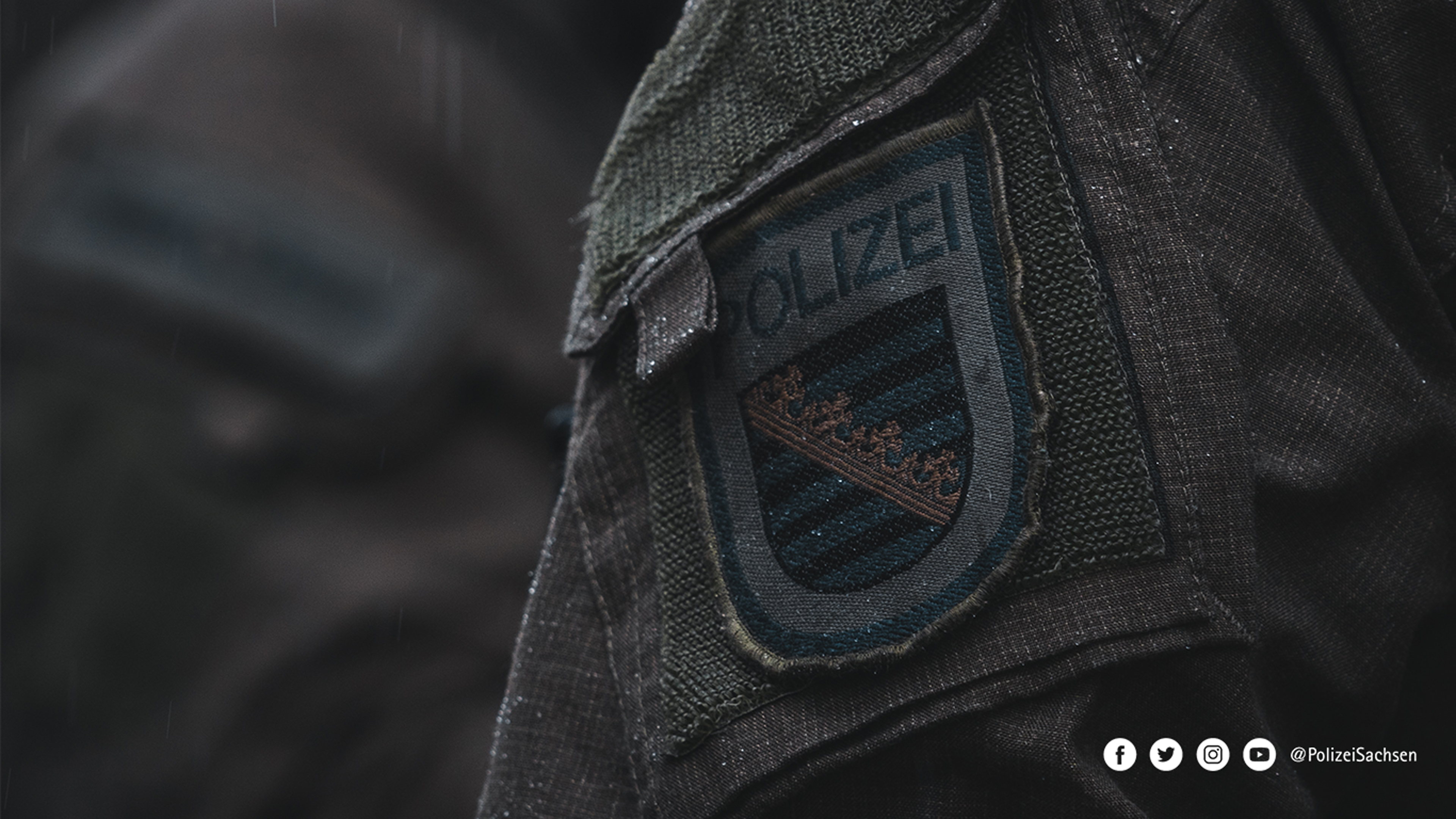 Nahaufnahme des Wappens der Polizei Sachsen auf einer dunklen Uniform.