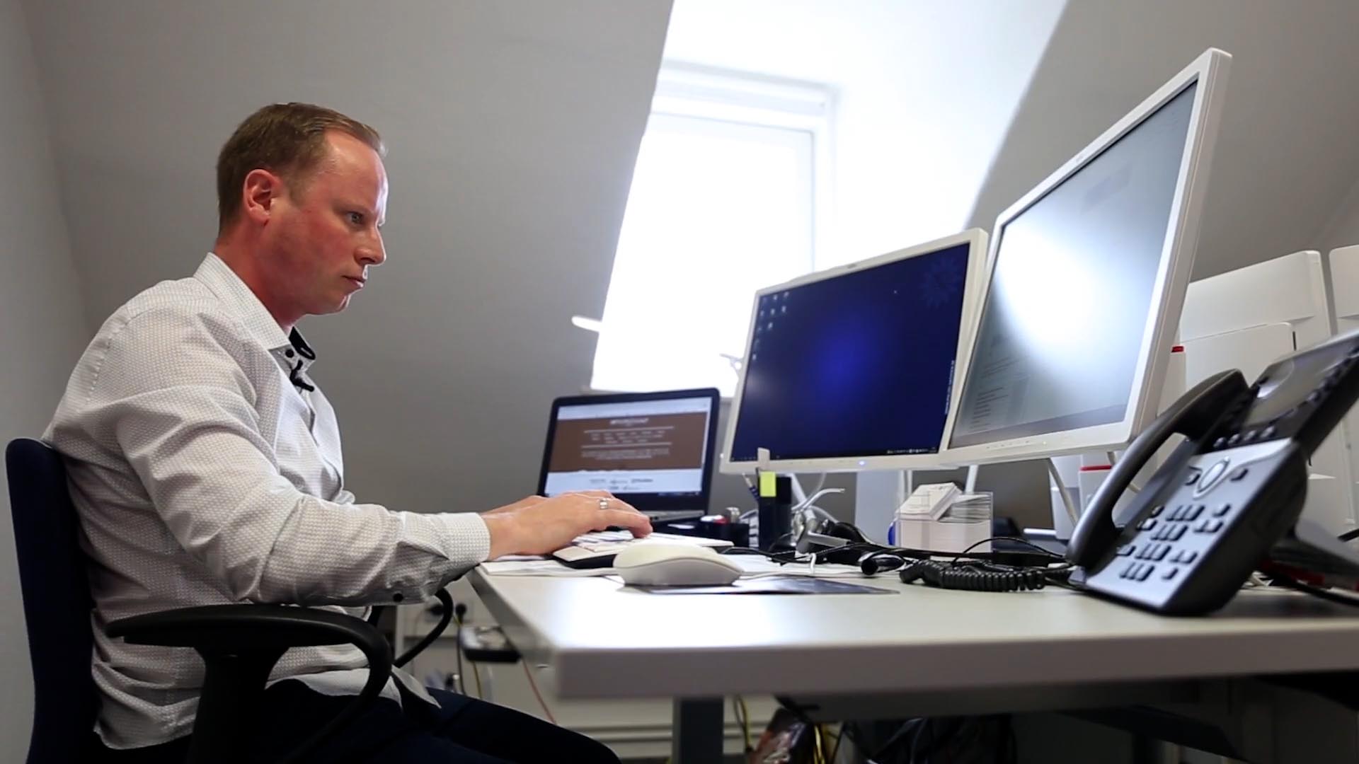 Ein Kollege der Cybercrime-Abteilung sitzt an seinem Arbeitsplatz. Vor ihm stehen drei moderne Monitore.